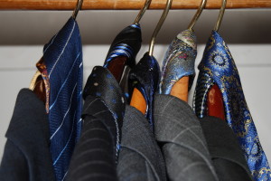 Picture of suit jackets with ties hanging in a closet.