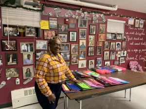 Photo of Sharon Curry in the Community Center. Pictures of inspirational people cover the walls and her student's notebooks fill the table.